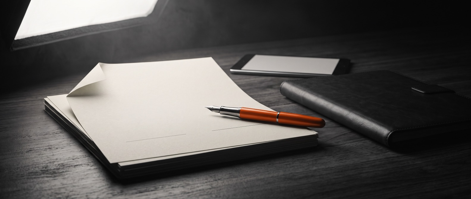 Contract on a desk with an orange pen on the signature line