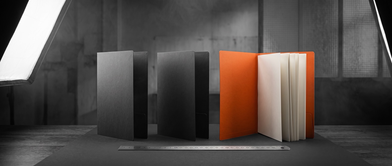 Three monthly report folders with a steel ruler